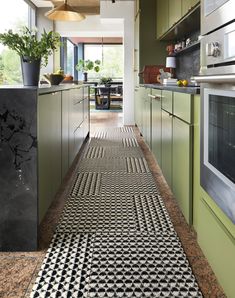 a kitchen with green cabinets and black and white patterned rugs on the floor next to an oven