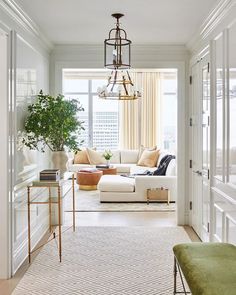 a living room filled with furniture and a chandelier hanging over the top of it