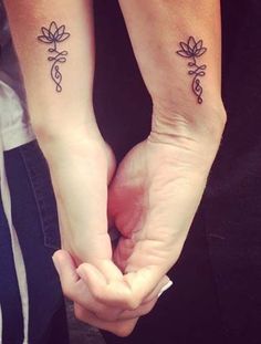 two people holding hands with matching tattoos on their arms and the other one has a small flower