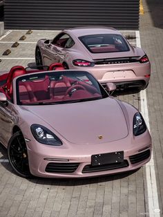 two pink sports cars parked next to each other