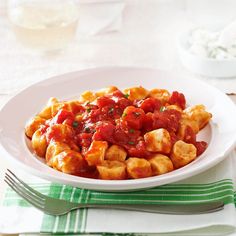 a white plate topped with pasta covered in tomato sauce