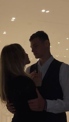 a man and woman standing next to each other in front of a wall with lights