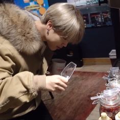 a woman looking at her phone while standing in front of some jars