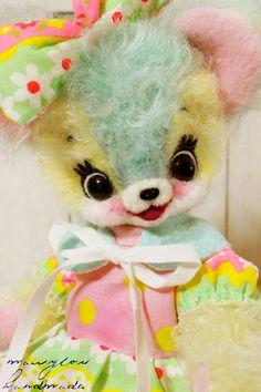 a small stuffed animal wearing a colorful dress and bow on it's head with polka dots