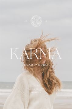 a woman standing on top of a beach next to the ocean with her hair blowing in the wind