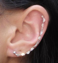 a close up of a person's ear with a chain attached to the side