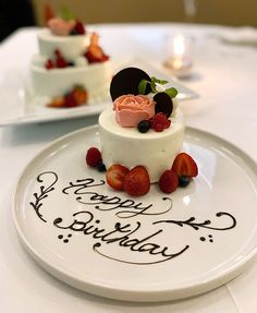 a white plate topped with a cake covered in frosting and strawberries on top of a table