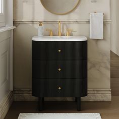 a bathroom vanity with a round mirror above it and two gold faucets on the sink