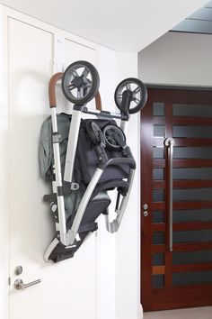 an umbrella and stroller hanging on the wall in front of a door with wheels attached to it