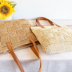 a straw bag sitting on top of a table next to a sunflower and a vase