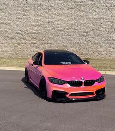 a pink and orange car parked in front of a building