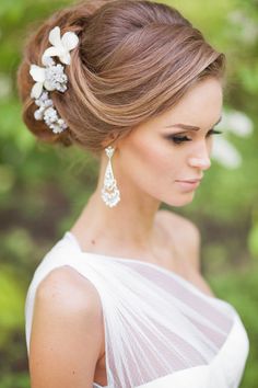 a woman wearing a white dress with flowers in her hair and pearls in her hair