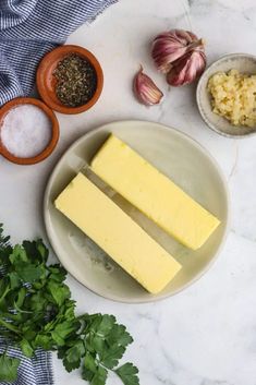 three slices of cheese on a plate with garlic, parsley and seasoning next to it