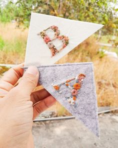 someone is holding up two pieces of fabric with flowers on them and the letters b are made out of felt