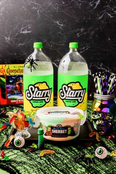 two bottles of starly water and candy on a table with halloween decorations around them