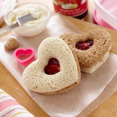 two heart shaped sandwiches sitting on top of a piece of paper next to some containers