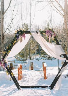 an outdoor wedding ceremony set up in the snow with white draping and flowers