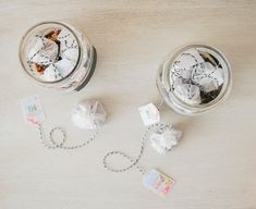 two glass jars filled with white flowers on top of a wooden table next to twine string