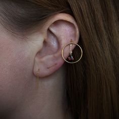 a close up of a person's ear with a gold hoop and bead