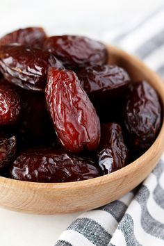 a wooden bowl filled with raisins on top of a white and black towel