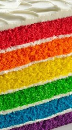 a multi colored cake with white frosting and rainbow stripes on it's side