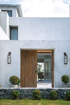 the front door is open and there are potted plants on the side of the house