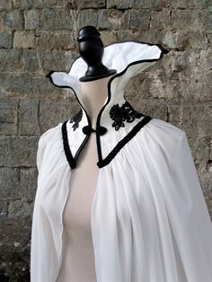 "Vampire wedding cape for halloween from Haizea Couture Dark couture costume cloak great for romantic goth masquerade party! This black and white bridal collar cape is made of off white silk fabric and off white chiffon fabric. It has black trimming and black lace applique details. CAPE DETAILS ⚬ Handmade in our atelier with lot of care. �⚬ Ready to ship. ⚬ Off white silk fabric. ⚬ Off white chiffon fabric. ⚬ Black trimming details and black lace applique. ⚬ Please provide a valid phone number so Goth Masquerade, Dark Couture, Dracula Cape, Cloak Black, Vampire Wedding, Black White Halloween, Elizabethan Collar, Funny Clothes, Cape Costume