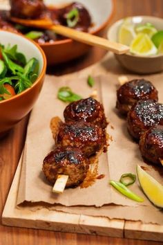 some meat skewers are on a cutting board next to a bowl of salad