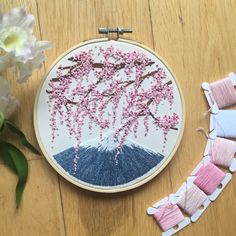 an embroidery project with pink and blue flowers on the table next to it is a piece of fabric that has been stitched together