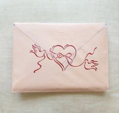 a pink envelope with a drawing of a heart and two hands on the inside of it