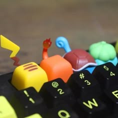 a toy train is sitting on top of a computer keyboard with yellow and green keys