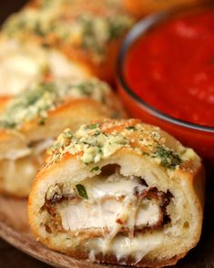 two pieces of bread with meat and cheese on it next to a bowl of tomato sauce