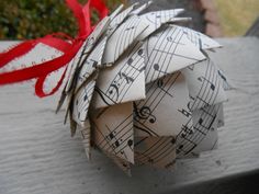 an origami ball with sheet music notes on it and a red ribbon tied around it