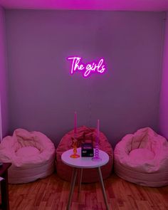 three bean bag chairs and a table in a room with purple lighting on the wall