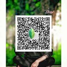 a person sitting on the ground with a qr code in front of their face