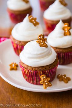 some cupcakes with white frosting and gold bows on them sitting on a plate