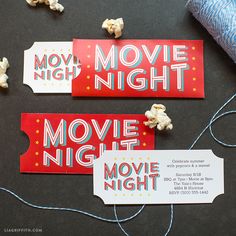 three movie night tickets sitting on top of a table next to a spool of thread