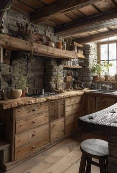 a rustic kitchen with stone walls and wooden cabinets, an island countertop and stools