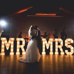 a bride and groom dance in front of mr and mrs letters