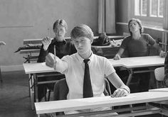 a group of people sitting at desks with one person raising his hand in the air