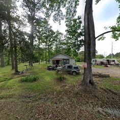 a car parked in front of a house next to trees and camping equipment on the ground