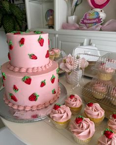 a pink cake and cupcakes on a table