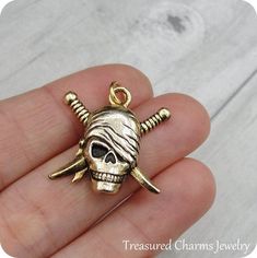 This Pirate Skull Charm comes with a gold jump-ring as pictured. Please note that photo is not to scale and may appear larger to show detail. Refer to exact measurements below.Additional attachments (lobster clasp, large-hole bead, necklace chains) are available from the charm-attachments drop-down menu.  For a visual example of the different attachments and what each one is best suited for, scroll through the photos until you see the example photo or visit https://etsy.me/2BY7DAW for detailed i Novelty Gold Metal Jewelry, Gold Skull-shaped Engraved Jewelry, Gold Skull Collectible Jewelry, Gold Skull Jewelry Collectible, Gold Skull Jewelry For Collectors, Handmade Gold Novelty Jewelry, Adjustable Gold Skull Bracelets, Gold Adjustable Skull Bracelets, Pirate Gifts