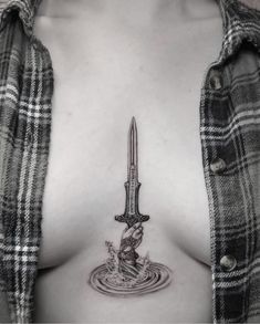 a woman's chest with a knife and water tattoo on the side of her breast