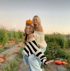 two women are hugging each other in a pumpkin patch