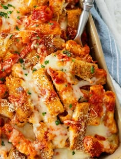 a casserole dish with meat, cheese and sauce in it on a blue towel