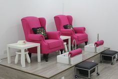 three pink chairs sitting on top of a wooden floor next to white tables and stools