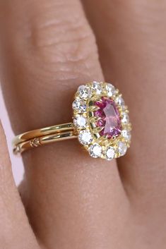 A symphony of sparkle shines brightly from this oh so easy to wear low-profile ring. At its center sits a glowing vivid natural and untreated pink sapphire. Sculpted around the sapphires exact portions by Jacob, bands can sit flush on either side. This ring is perfect as an engagement ring or part of a fun party stack. Divine and bright single antique cut diamonds surround adding a unique old-world charm. Luxury Pink Sapphire Ring With Brilliant Cut, Luxury Pink Sapphire Ring With Prong Setting, Pink Cluster Ring With Round Cut, Pink Cluster Ring With Halo Setting, Pink Sapphire Ring Fine Jewelry, Pink Round Cut Cluster Ring Fine Jewelry, Exquisite Pink Sapphire Gemstone Rings, Pink Sapphire Ring With Halo Design For Formal Occasion, White Gold Pink Sapphire Ring For Wedding