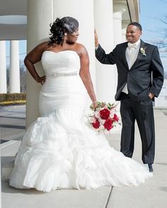 a man and woman in formal wear standing next to each other on a sidewalk with columns