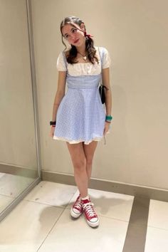 a girl in a blue and white dress standing next to a mirror with her hands on her hips